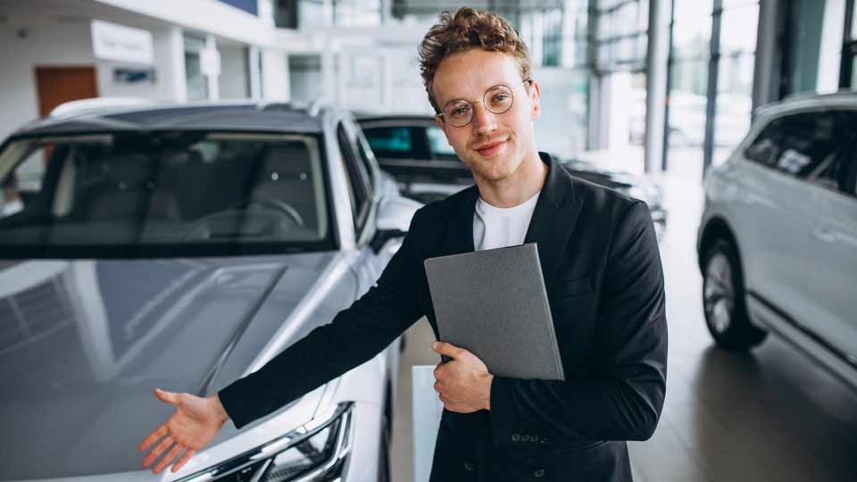 Ein Verkäufer zeigt auf ein Auto und erklärt dem Kunden die Konditionen beim Auto verkaufen Herrenberg